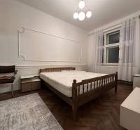 A bedroom in a 3-room apartment with a simple bed and a floor with a wood decor.