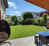 The garden of a family house in Kotrčiná Lúčka with garden furniture and a view of the countryside.