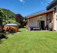A family house in Kotrčiná Lúčka with a terrace and a hot tub in the middle of a green garden.