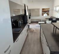 Modern kitchen with wood-patterned flooring and comfortable furniture in a family house.