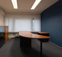 An office with desks and cabinets in a 4-room apartment, blue wall, wooden furniture.