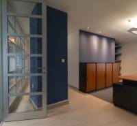 Office space with glass doors, a blue wall, and wooden furniture.