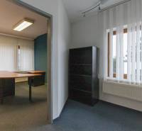 Office space in a 4-room apartment with shelves, a desk, and vertical blinds.