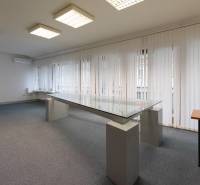 Office room with a glass desk, carpeted floor, and vertical blinds.