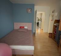 A room in a 3-room apartment with a bed, a shelf, and a floor with a wooden decor.