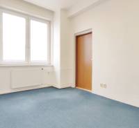 Offices with blue carpet, plain walls, and a window next to the door.