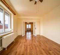 Spacious room in a 2-room apartment with wood-patterned flooring and large windows.