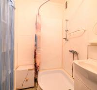 A bathroom in a 2-room apartment with a bathtub, sink, and shower with a plastic curtain.