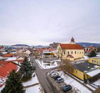 Winter landscape in Fiľakovo with a church, rooftops of houses, and snowy streets.