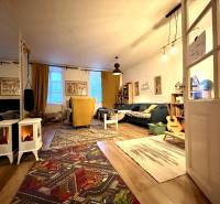 Living room with a sofa, armchairs, carpet, and wooden decor flooring in a family house.