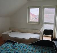 Children's room in a family house with two beds and an armchair, floor with wooden decor.