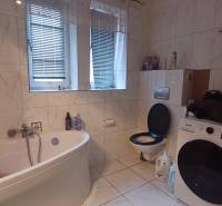 A bathroom in a 2-room apartment with a washing machine, a bathtub, and a toilet, tiled with tiles.