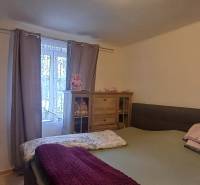 Bedroom in a 2-room apartment with a bed and a wardrobe, light curtain on the window.