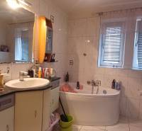 A bathroom with a bathtub, double window, and white tiles in a 2-room apartment.