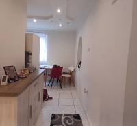 A hallway in a 2-room apartment with wooden decor and a dining table at the end.