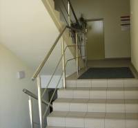 A staircase with stainless steel railing leads to offices with tiling.