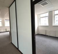 Offices with white walls, a glass partition, and large windows; carpeted floor.