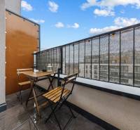 The balcony of a one-room apartment on Zuzany Chalupovej in Bratislava - Petržalka, with wooden seating.