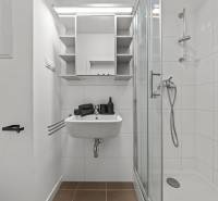 Bathroom with white tiles, a shower enclosure, and a sink.