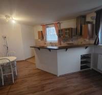 Dining area with wood-patterned flooring in a 3-room apartment, open kitchen with a bar counter.