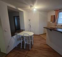Dining area in a 3-room apartment with a wooden-patterned floor and a white table.