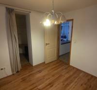 A room with a wooden decor floor, a wardrobe, and a curtain in a 3-room apartment.