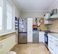 A kitchen in a 3-room apartment with a wooden decor floor, equipped with appliances.