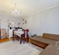 Living room in a three-room apartment with carpets and a chandelier, dining for four people.