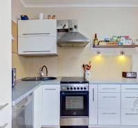 A kitchen in a 3-room apartment with a kitchen unit, stove, and floor with a wood decor.