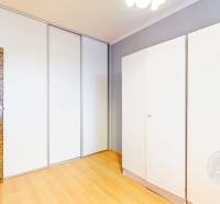 A bright room in a 3-room apartment with a wood-patterned floor and a built-in wardrobe.