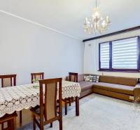 Living room with a dining table, sofa, and chandelier in a three-room apartment.