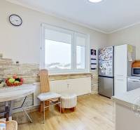 A kitchen of a three-room apartment with a seating nook and a floor with a wood decor.