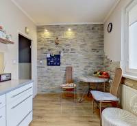 A kitchen in a 3-room apartment with a wooden decor floor and a brick wall cladding.