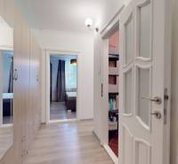 A hallway with a wood-patterned floor in a 2-room apartment, built-in wardrobe and doors.