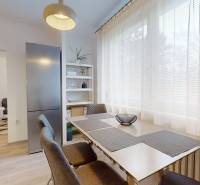 Dining area in a 2-room apartment with a wooden decor floor and light furniture.