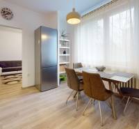 Kitchen of a 2-room apartment with a wooden decor floor, dining table, and refrigerator.