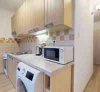 A kitchen in a 2-room apartment with a wooden decor floor and a kitchen unit.