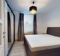 Bedroom with a large bed, wardrobe, and wooden decor flooring in a 2-room apartment.