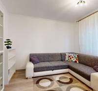 Living room in a two-room apartment with a sofa, shelves, and a floor with a wooden decor.