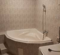 A bathroom in a family house with a corner bathtub and tiles.