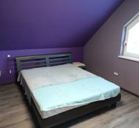 Purple bedroom with a bed and wood-patterned floor in a family house.