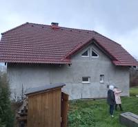 A family house in Orovnica, gable roof, two people on the lawn.