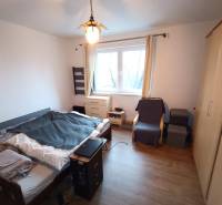 Bedroom in a family house with a bed, wardrobes, an armchair, and a floor with a wooden decor.