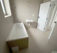 Bathroom in a 2-room apartment with a bathtub, sink, and light tiles.