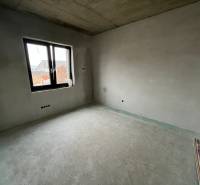 Interior of an empty room in a family house with a window and raw floor.