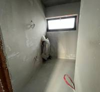 An unfinished room in a family house with a window and exposed piping.