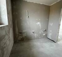 Empty room in a 3-room apartment with unfinished concrete walls and floor.