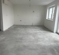 An empty room in a 3-room apartment with a concrete floor and windows.