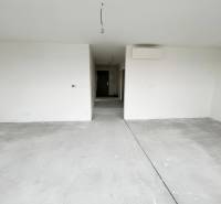 An empty room in a 3-room apartment with a concrete floor and white walls.