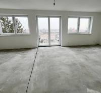 A spacious room with large windows in a 3-room apartment, white walls, and a concrete floor.